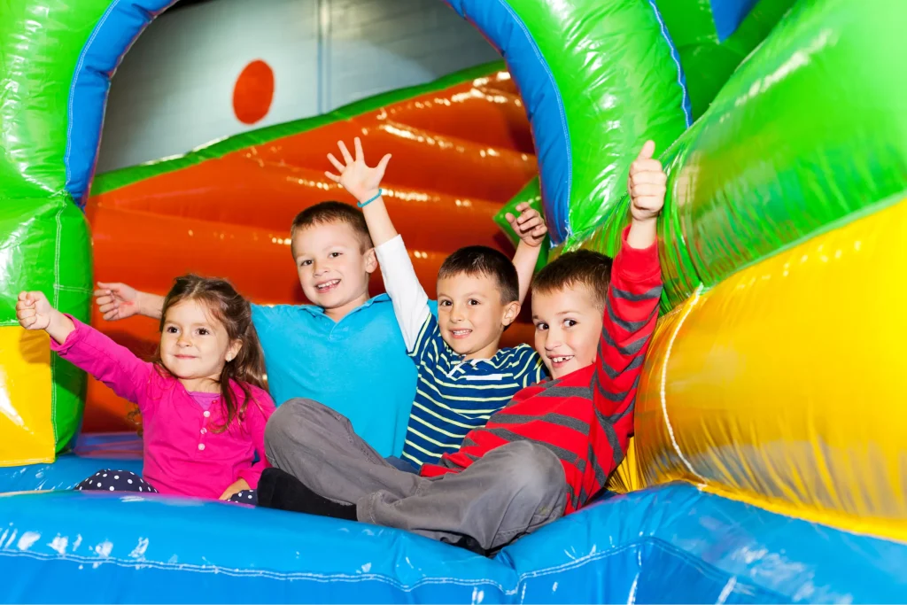 A group of children joyfully playing inside a bouncy castle at an indoor playground.