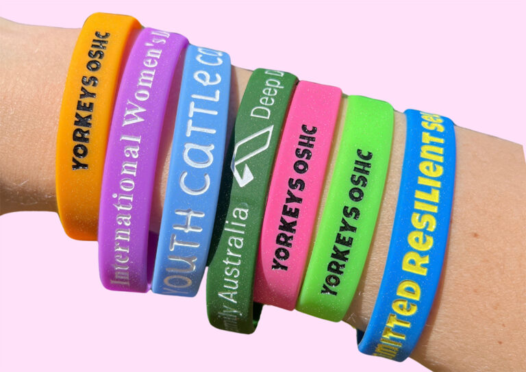 A person wearing a collection of custom glitter-finish wristbands.