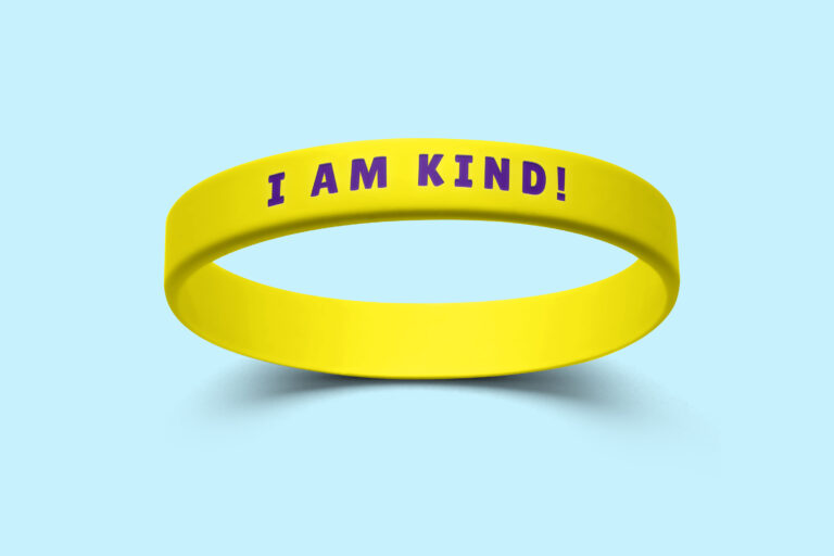 A yellow silicone wristband featuring the message "I am kind!"