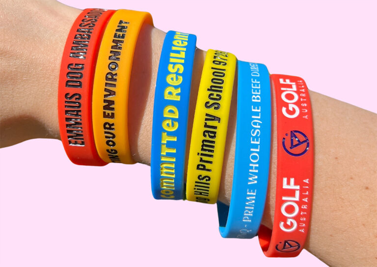 A close-up of a variety of custom silicone wristbands in different colours.