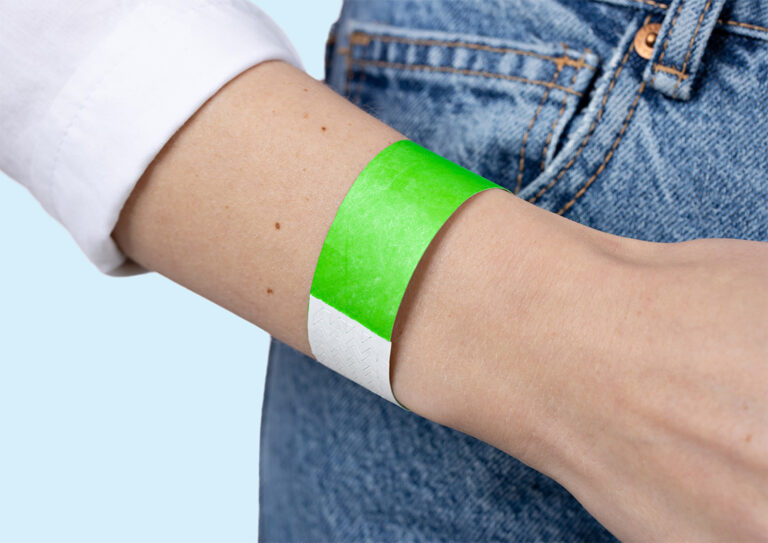 A close-up of a person's wrist displaying a plain green Tyvek wristband.